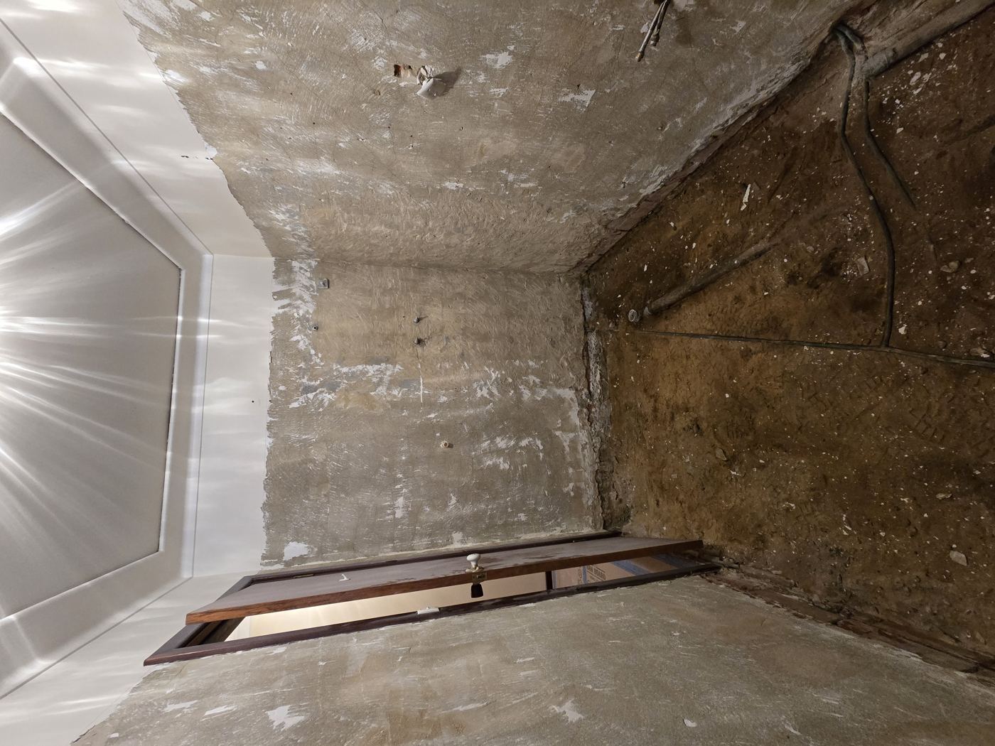 Bathroom mid strip-out, walls and floor stripped back